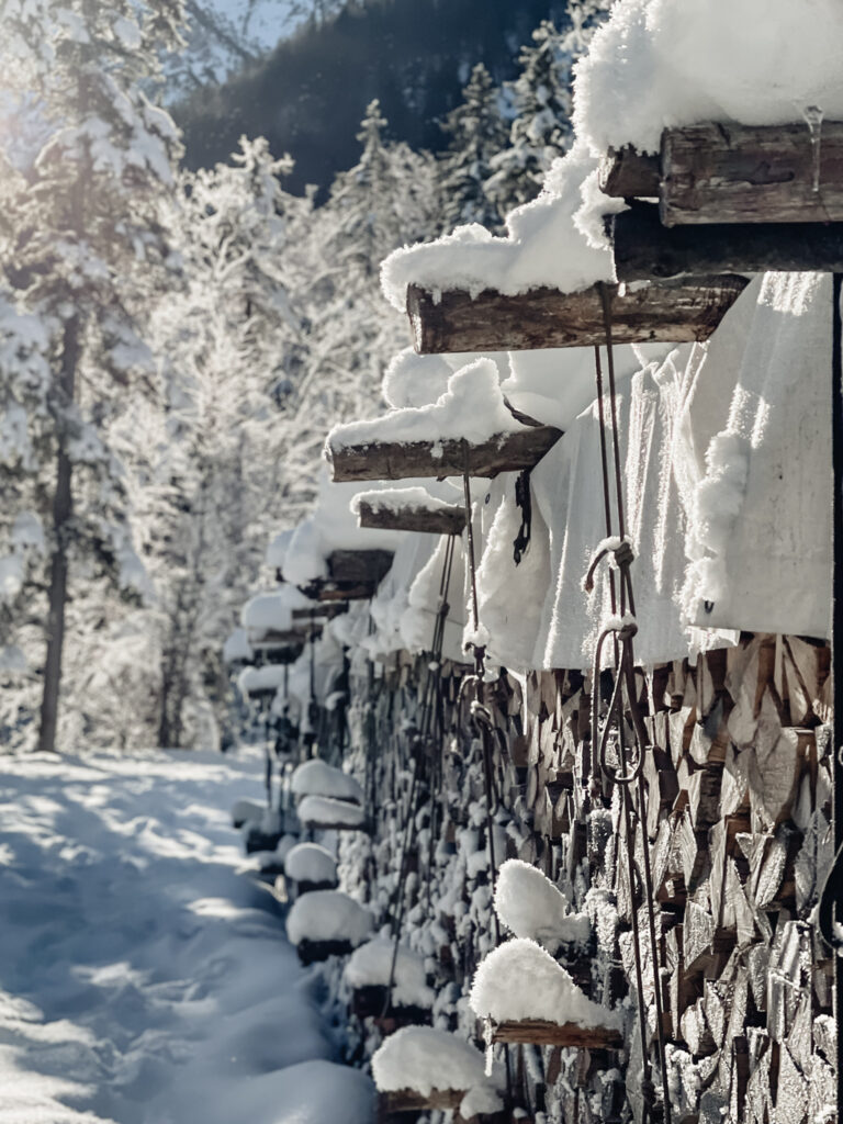 Winterwandern-Winterwanderung-Wildbad-Kreuth-Siebenhüttenalm-Kleine-Wolfsschlucht-Winterlandschaft-Schnee-Sonne-Winter-Wonderland-Mangfallgebirge-gestapeltes-Holz-living.elements